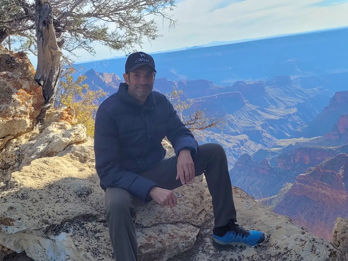 Ori, co-founder of Innsider and a host at White Camel in Kanab, sitting on the rim of the Grand Canyon